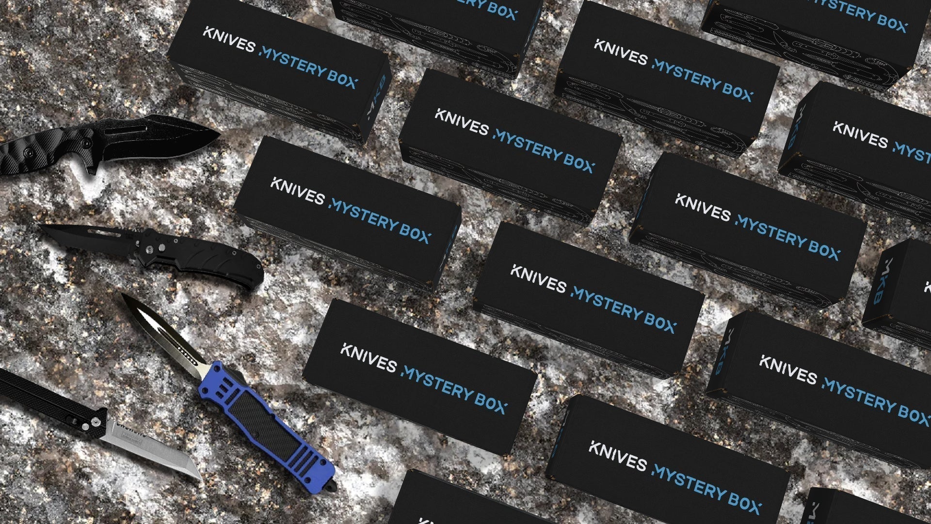 Collection of mystery knife boxes displayed on textured rock background, with assortment of mystery knives to the left.