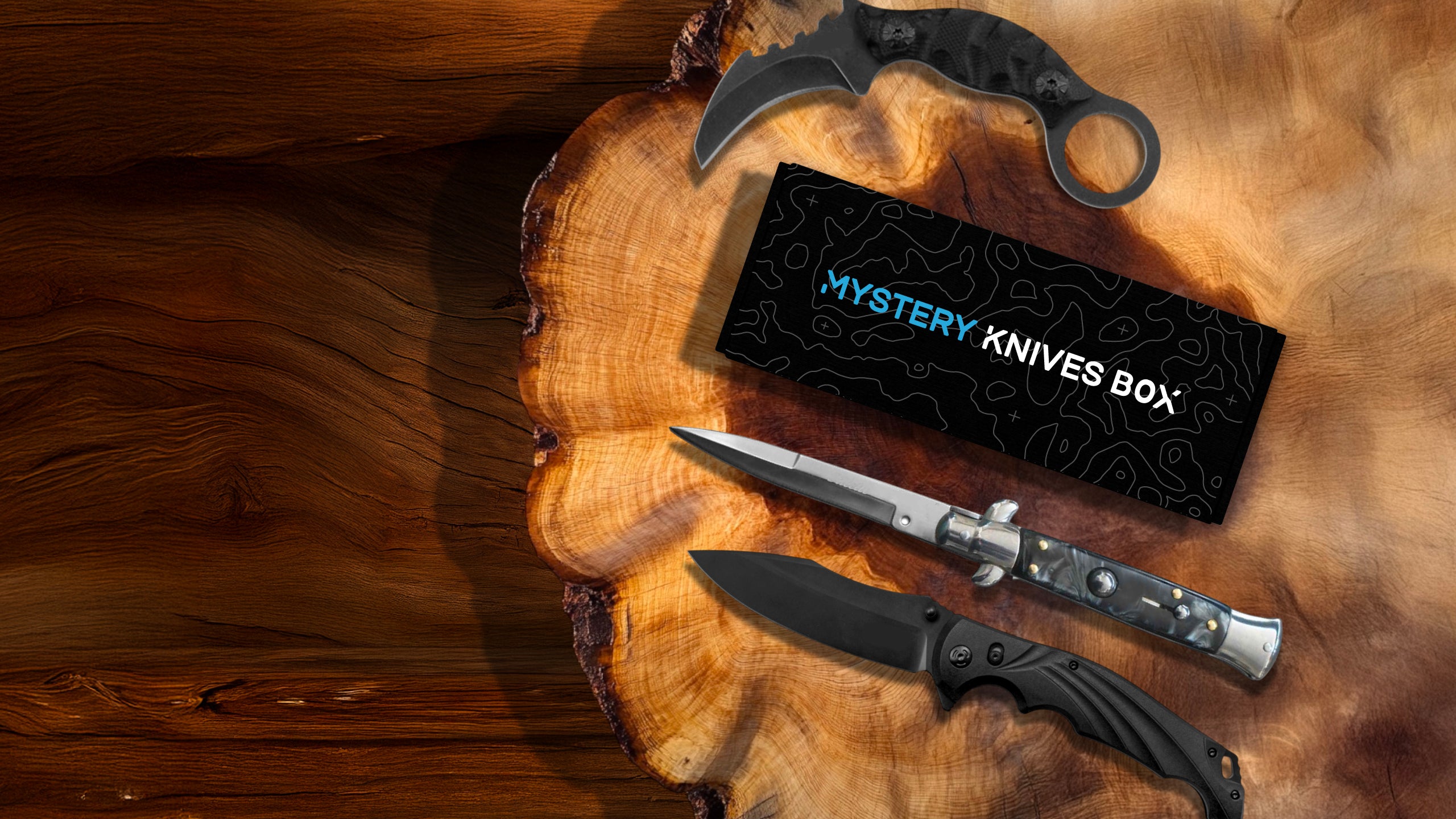 Mystery Knives Box displayed next to karambit, stiletto, and black pocket knife on wood board